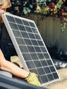 A worker installs a solar panel in a garden, promoting clean energy.